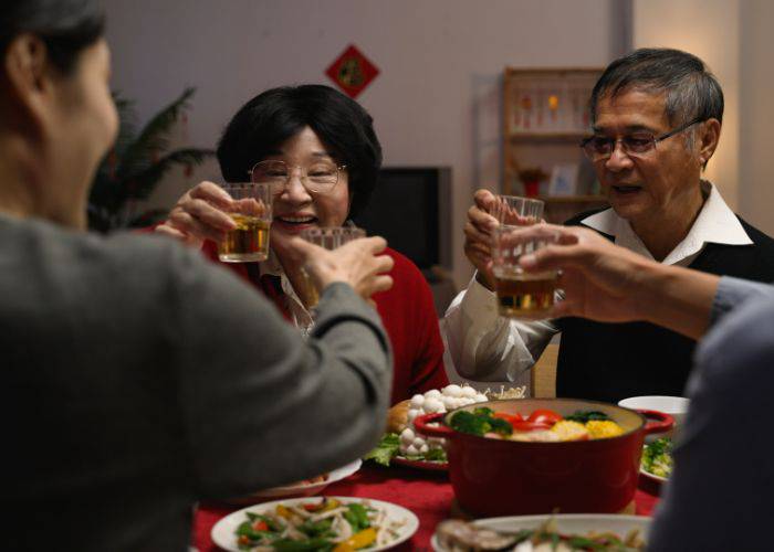 A family raising their glasses at the dinner table, celebrating the start of a new year.